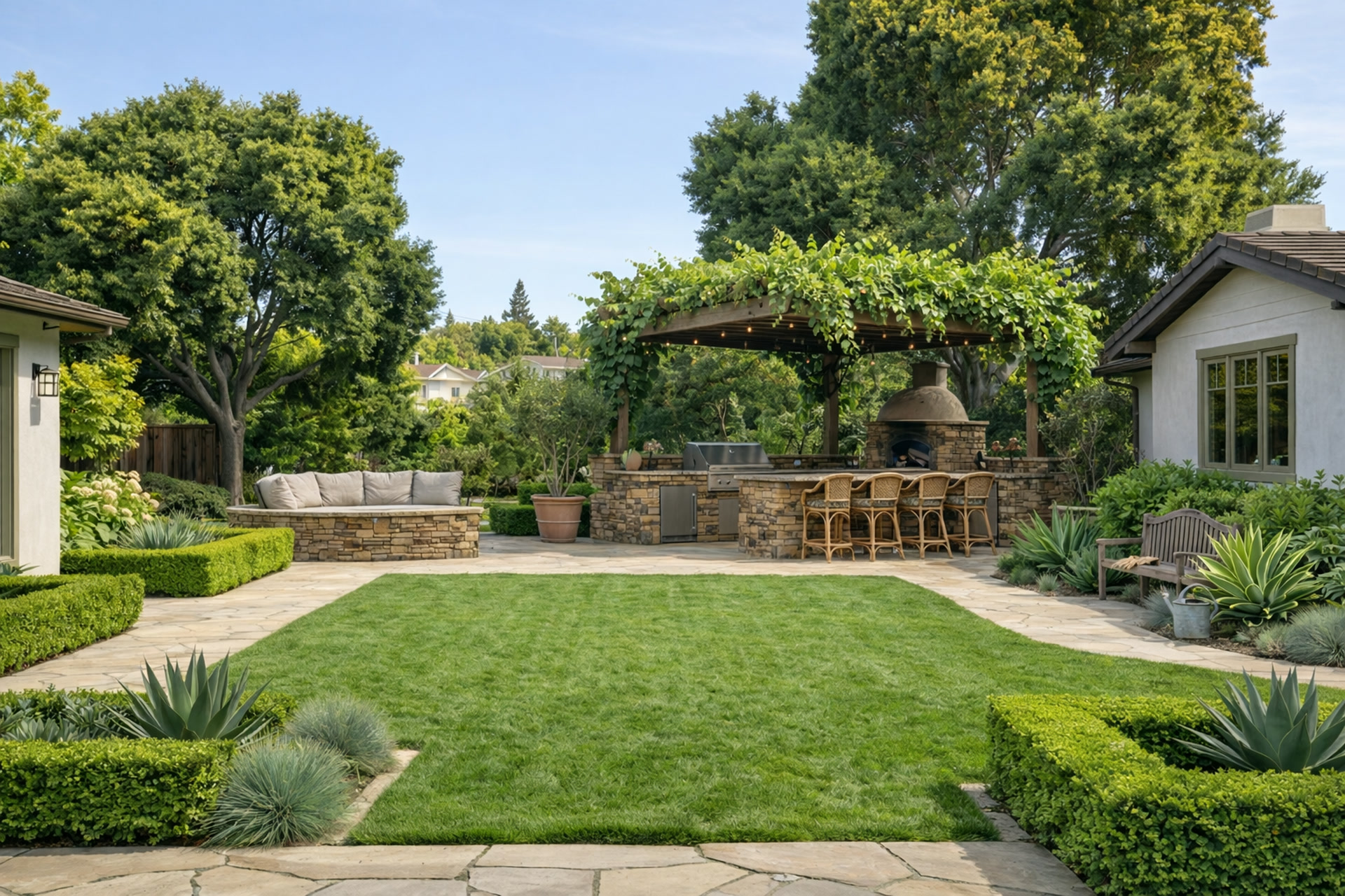 Backyard with manicured lawn, stone patio, outdoor kitchen with pergola, and boxwood hedges.